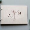 Ξύλινο Βιβλίο Ευχών Γάμου με Χάραξη W020 Βιβλίο ευχών ξύλινο με τα αρχικά των ονομάτων και floral λεπτομέρεια.